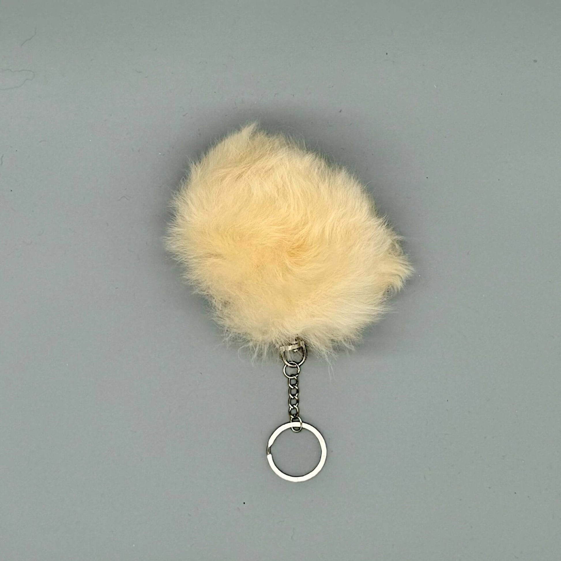 Flauschiger beige Alpaka Bommel Schlüsselanhänger aus Alpakafell mit silberner Schlüsselringschnalle.