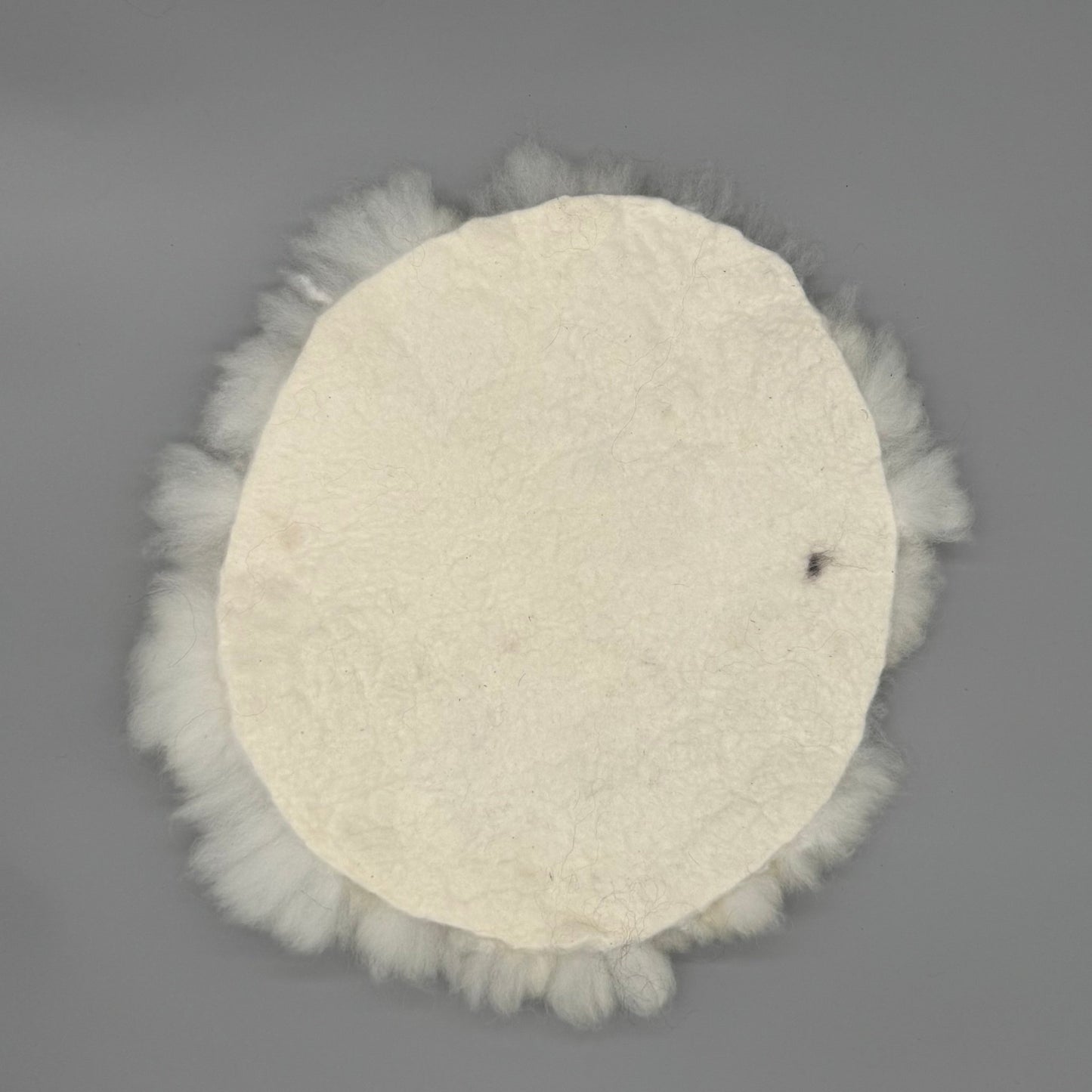 Alpaka Sitzkissen aus weißer Alpakawolle, handgefilzt und rund, Durchmesser ca. 40 cm.