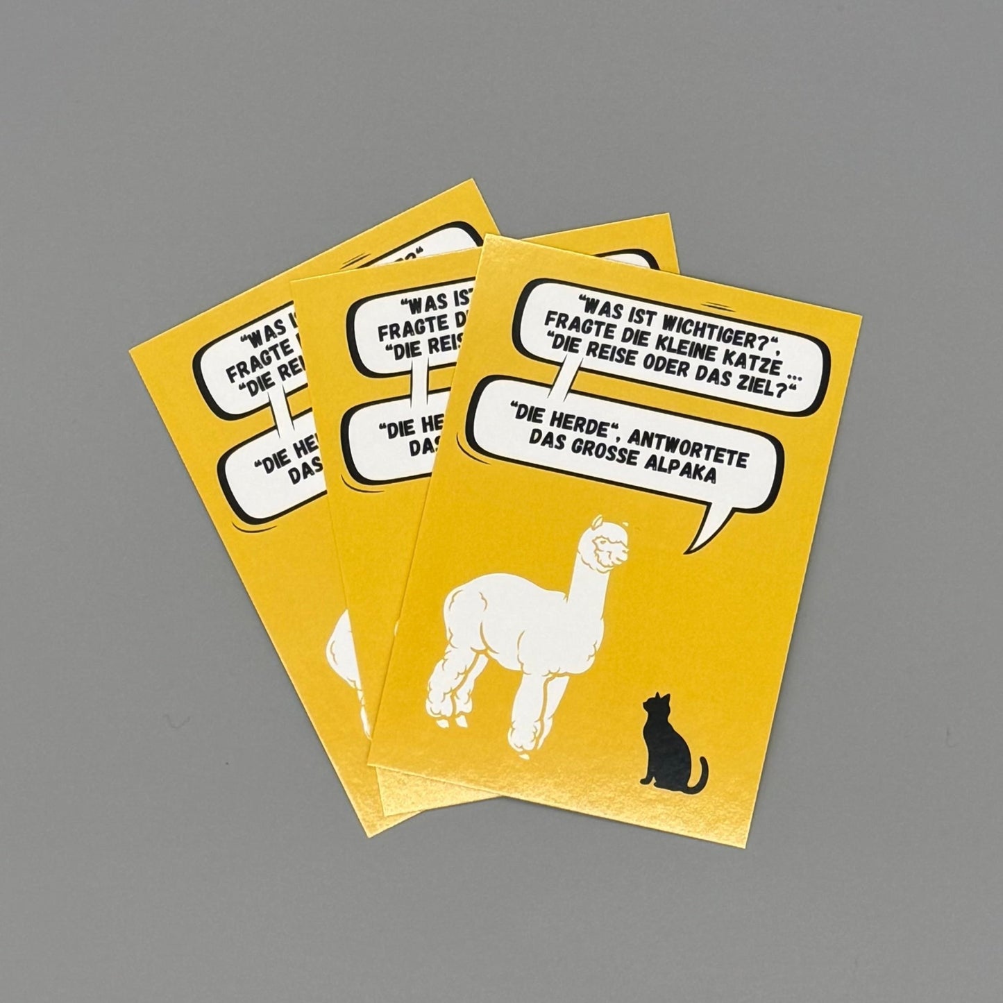 Alpaka Postkarte mit Spruch – „Was ist wichtiger?“, großes Alpaka und kleine Katze auf gelbem Hintergrund
