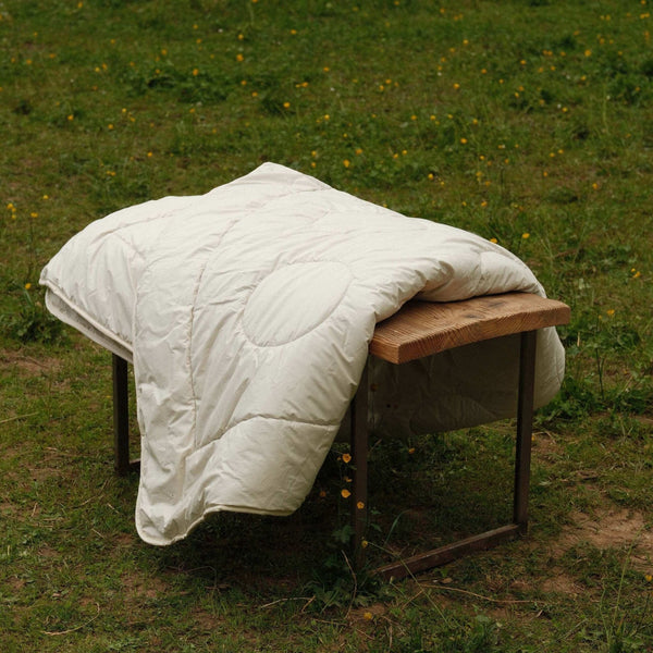 Alpaka Bettdecke auf einer Holzbank im Freien, ideal für Winter- und Herbstnächte.