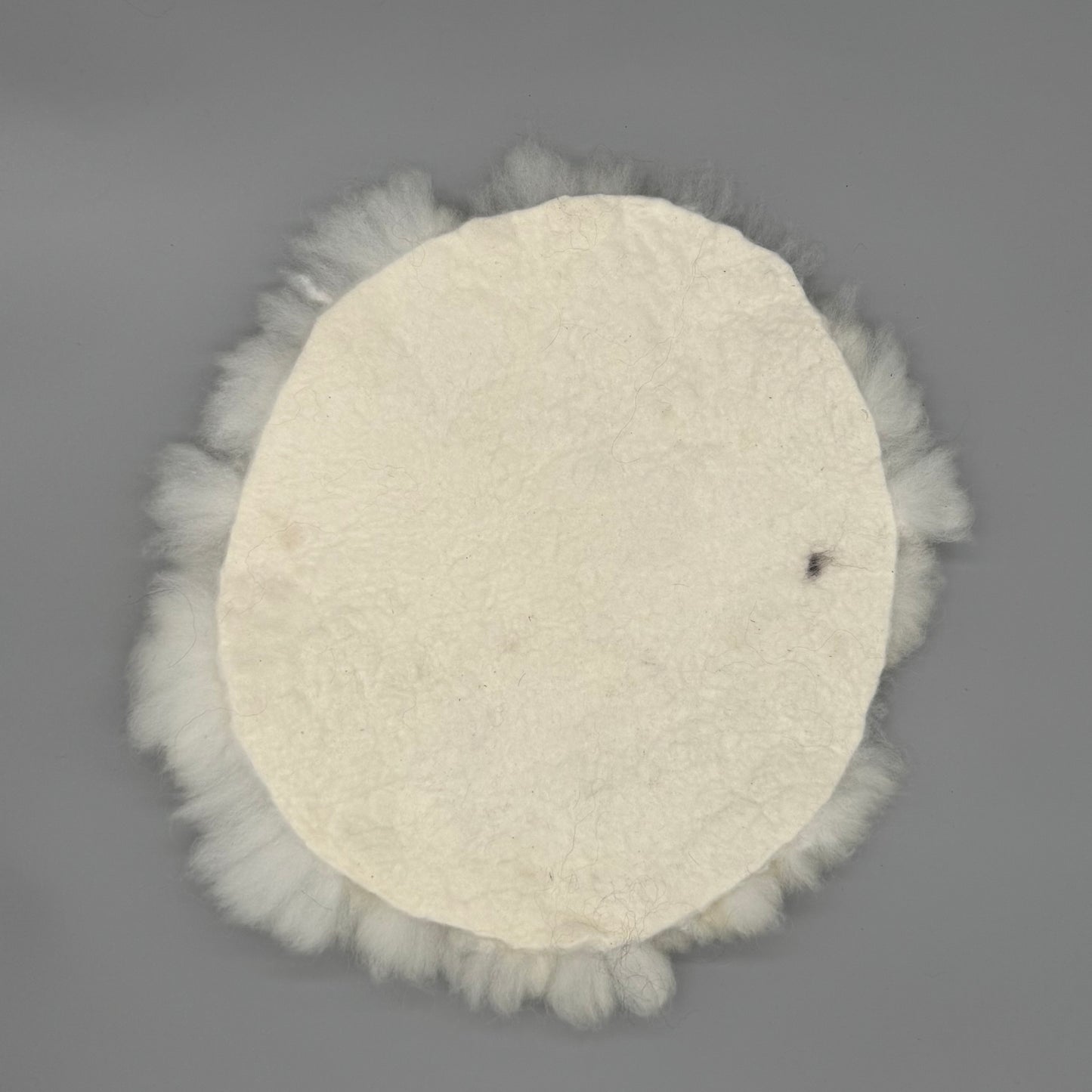 Alpaka Sitzkissen aus weißer Alpakawolle, handgefilzt und rund, Durchmesser ca. 40 cm.