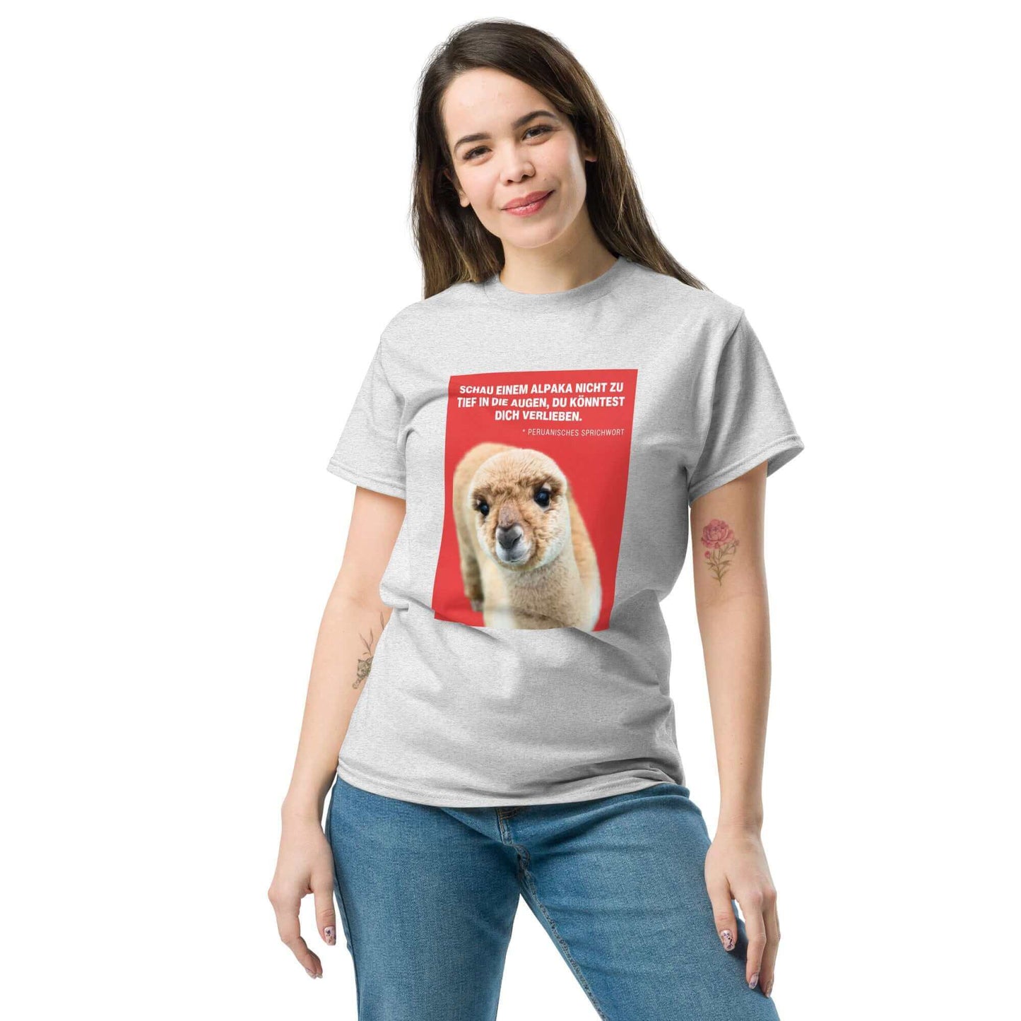 Frau trägt graues Unisex Alpaka T-Shirt mit liebevollem Alpaka Greta Print und Spruch auf rotem Hintergrund. Hochwertiges Baumwollshirt für Alpaka Fans.